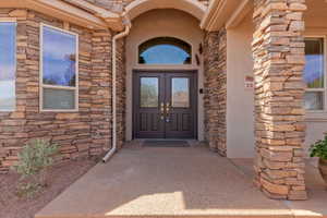 Property entrance with stone siding, stucco siding, and french doors