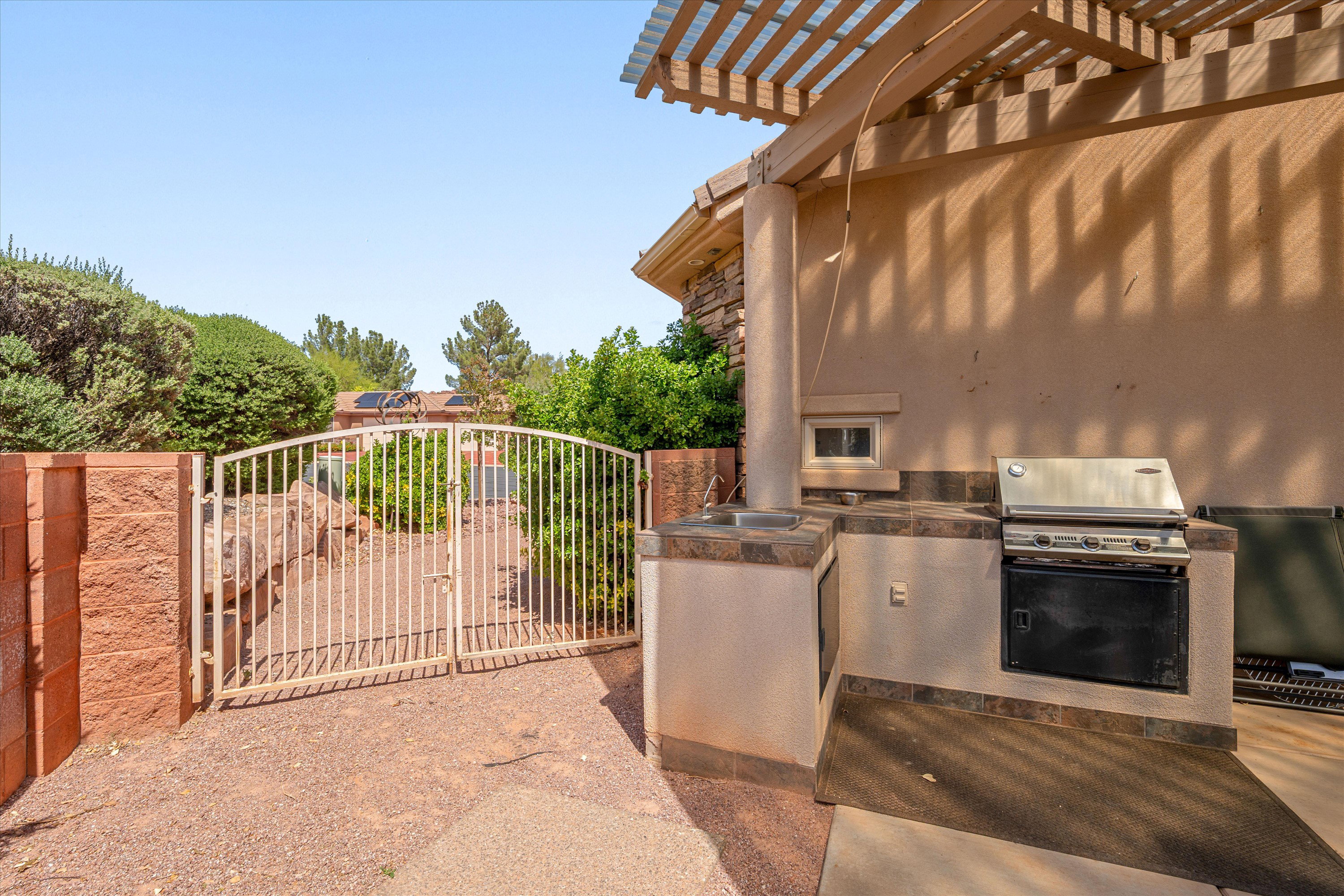 View of patio featuring area for grilling, a gate, and a pergola