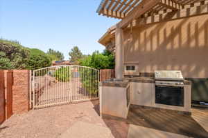 View of patio featuring area for grilling, a gate, and a pergola