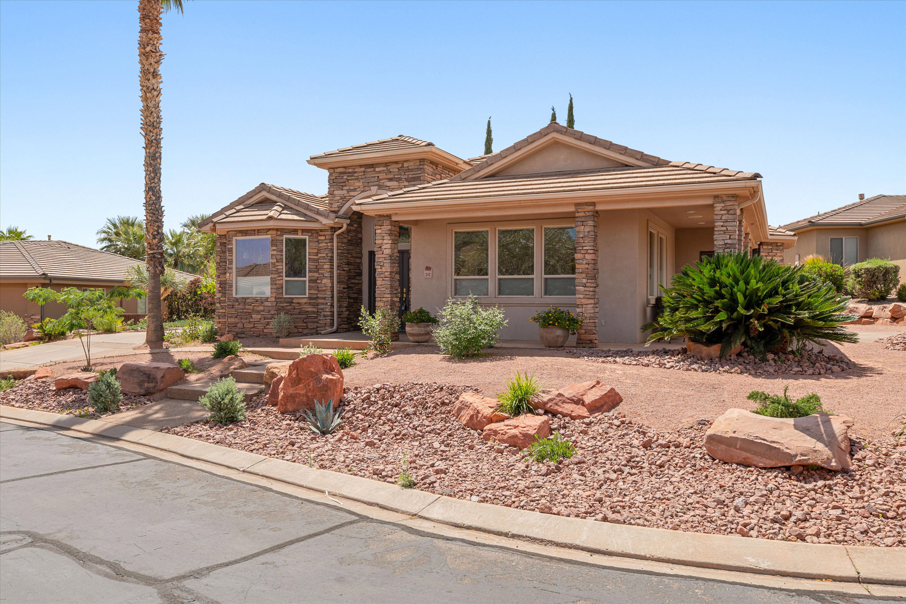 View of front of property with stone siding, stucco siding, a porch, and a tiled roof