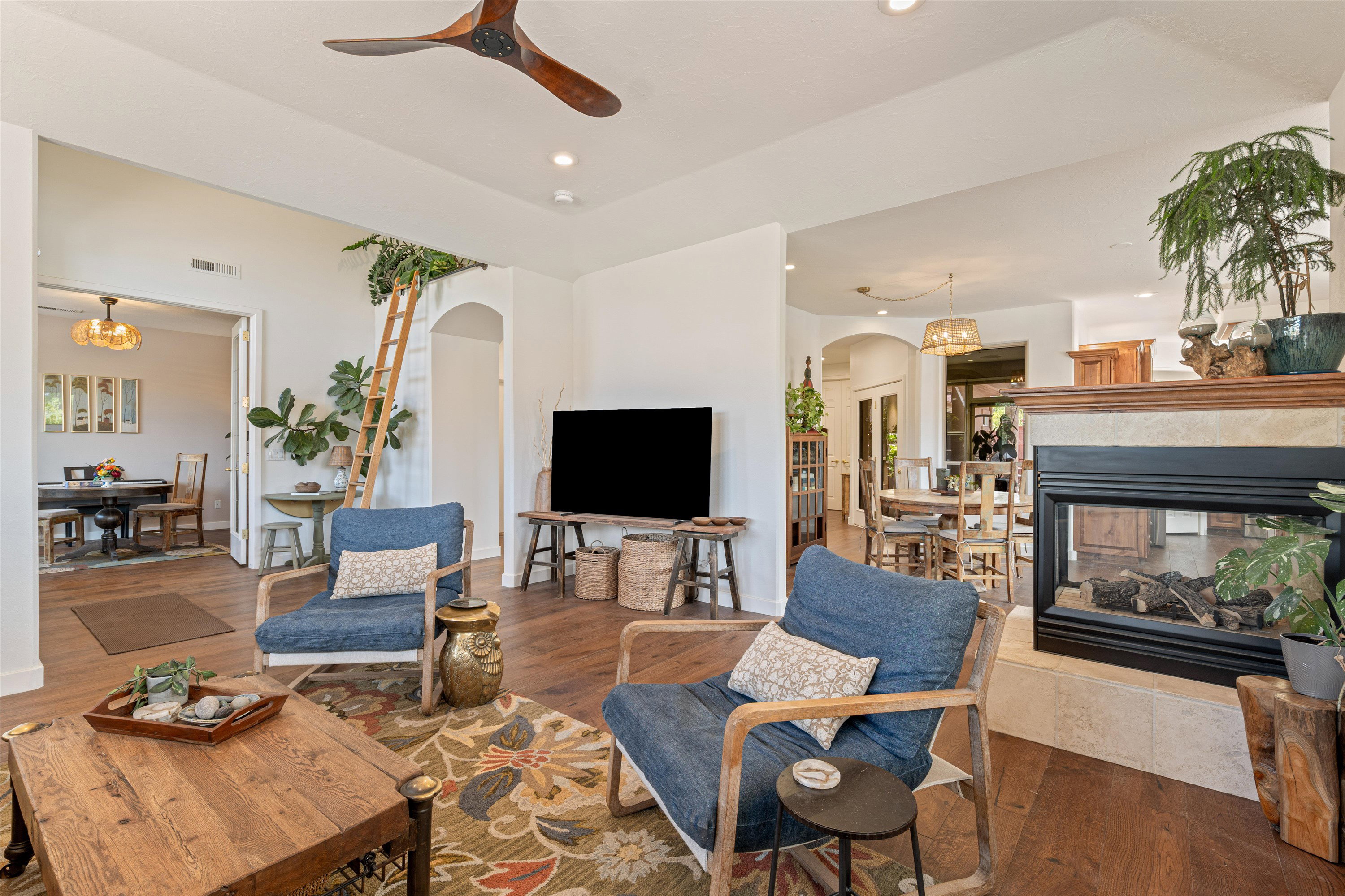 Living area with arched walkways, a ceiling fan, wood finished floors, a fireplace, and recessed lighting