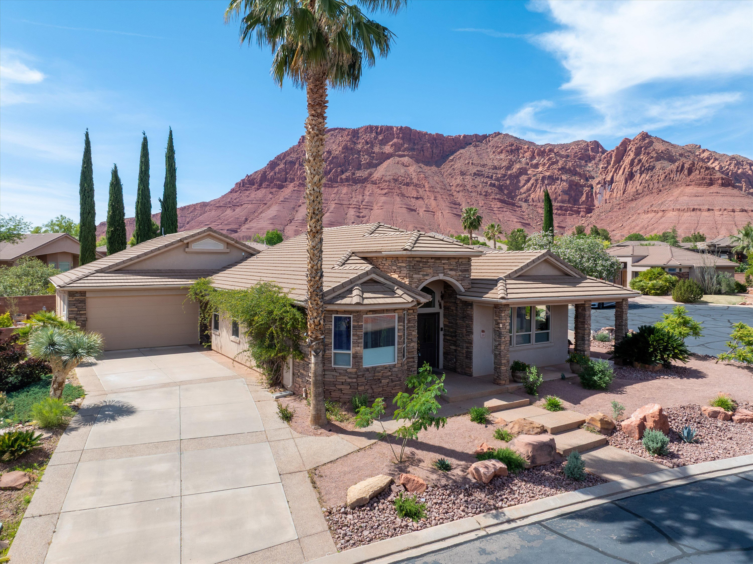 View of front of house featuring concrete driveway, stone siding, a mountain view, and a garage