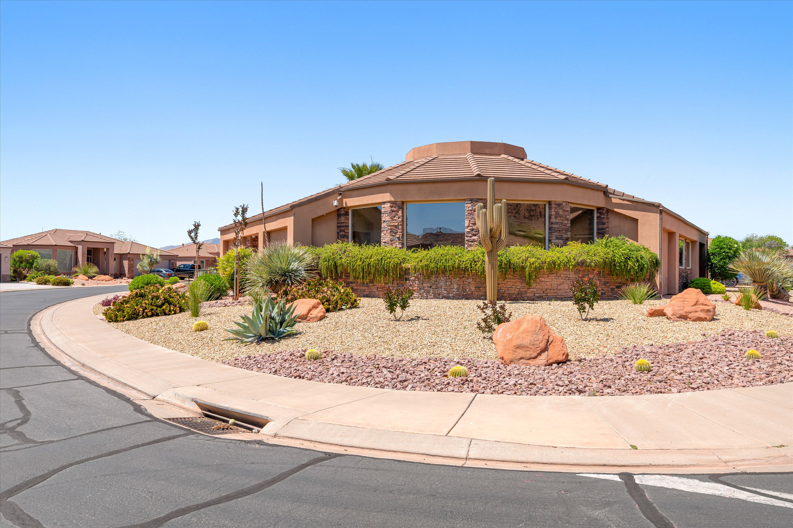 Desert-inspired landscaping featuring a curved sidewalk, a variety of low-maintenance plants, gravel ground cover, and natural rock accents