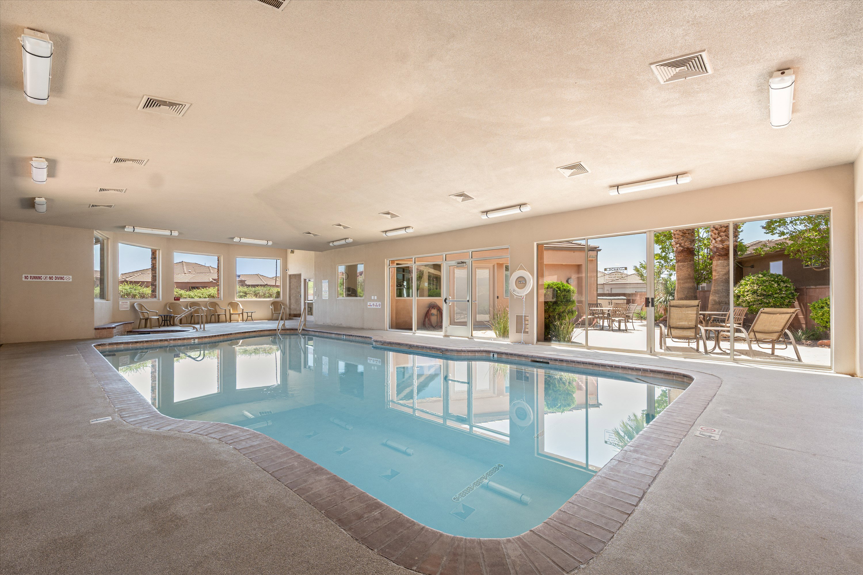 Indoor swimming pool with concrete decking, large windows, and direct patio access