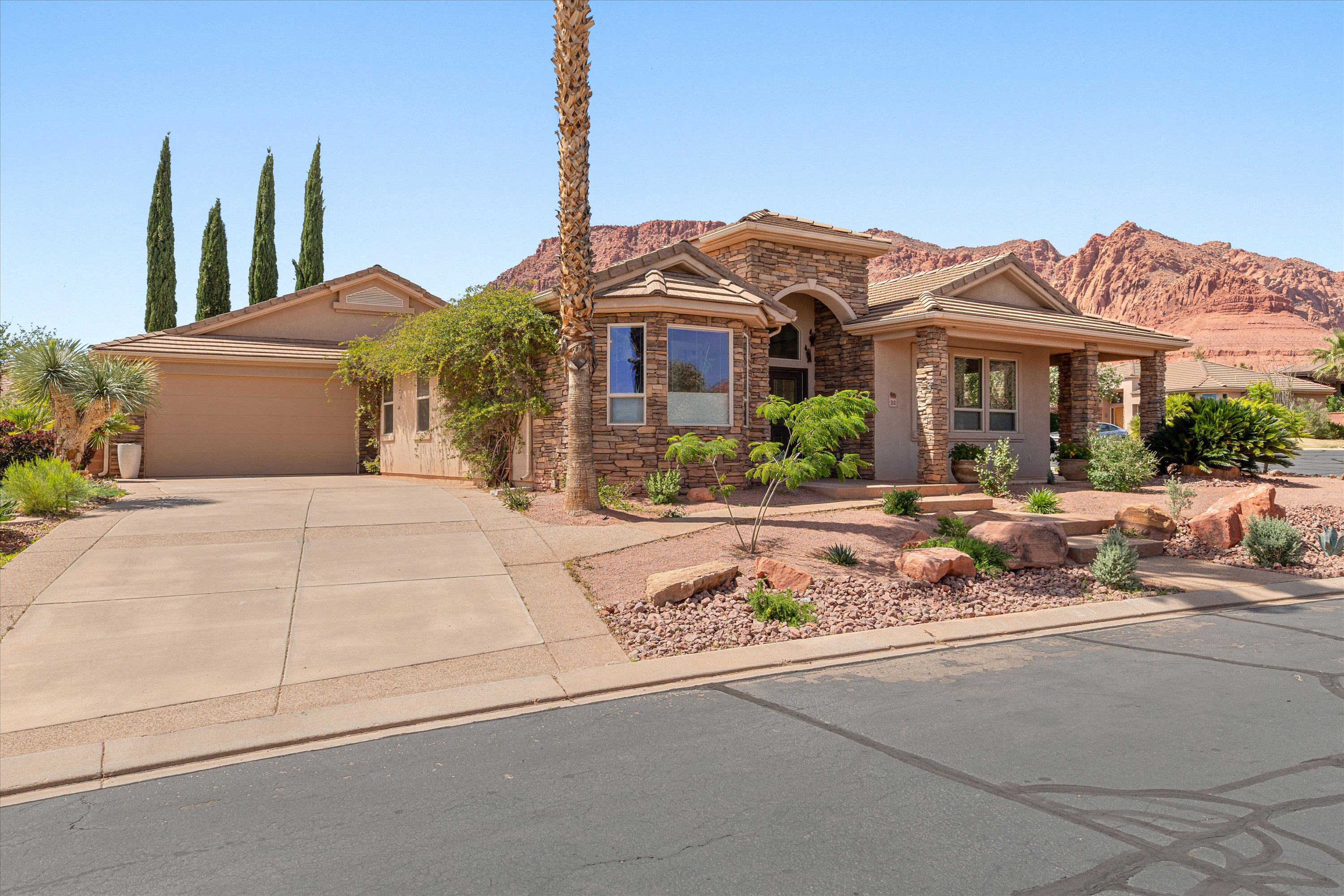 View of front of property featuring stone siding, driveway, and a garage