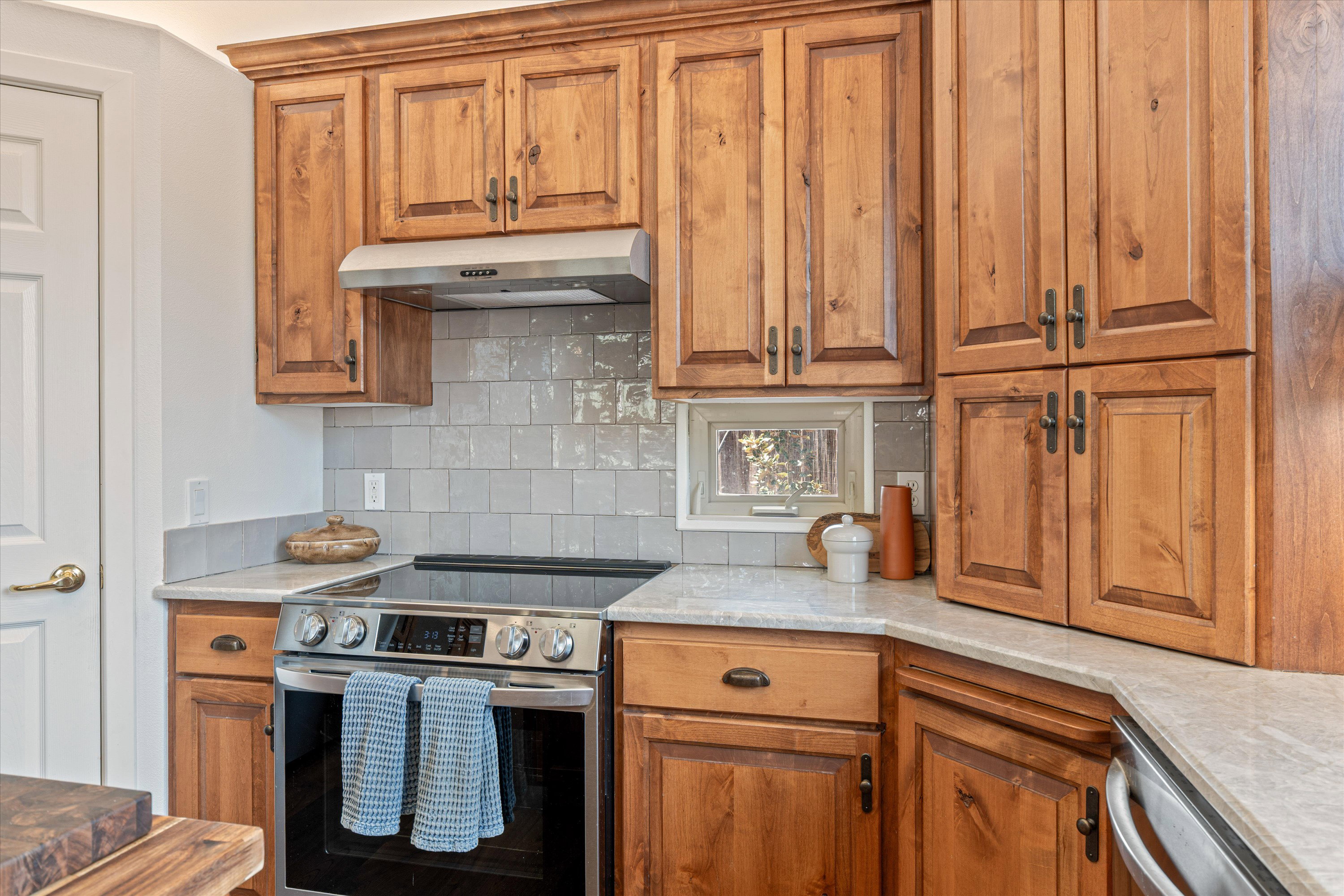 Kitchen with stainless steel appliances, light stone countertops, wood finish cabinetry, and backsplash