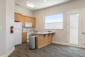 Kitchenette featuring wood cabinetry, white appliances, a built-in sink, and a large window