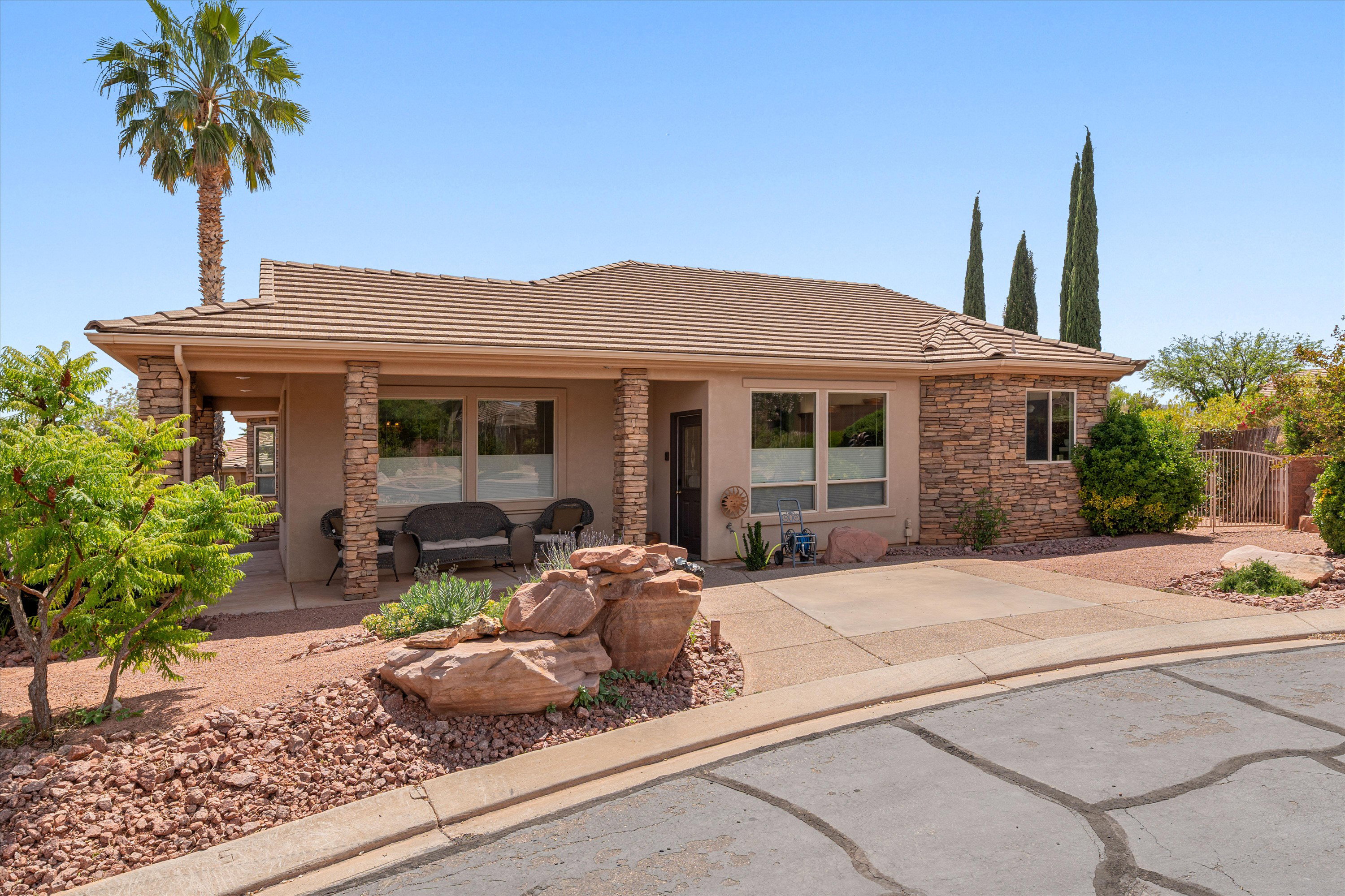 View of front of property with stone siding, a tile roof, stucco siding, and covered porch