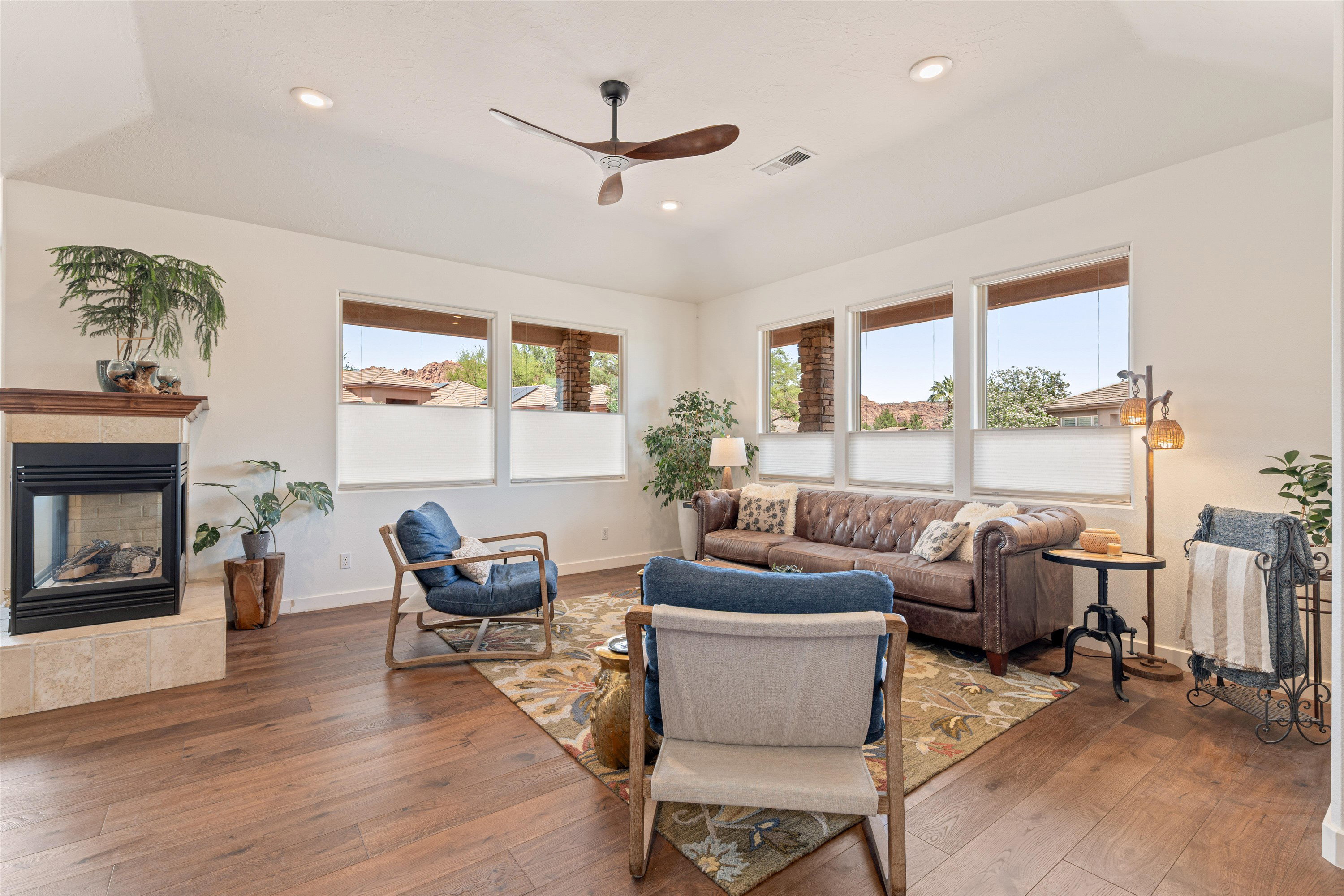 Living area featuring ceiling fan, hardwood / wood-style floors, vaulted ceiling, recessed lighting, and a tiled fireplace