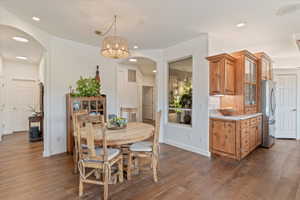 Dining space with arched walkways, dark wood finished floors, and hanging lights