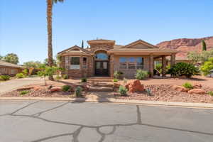 View of front facade with stone siding, french doors, a tile roof, covered porch, and stucco siding