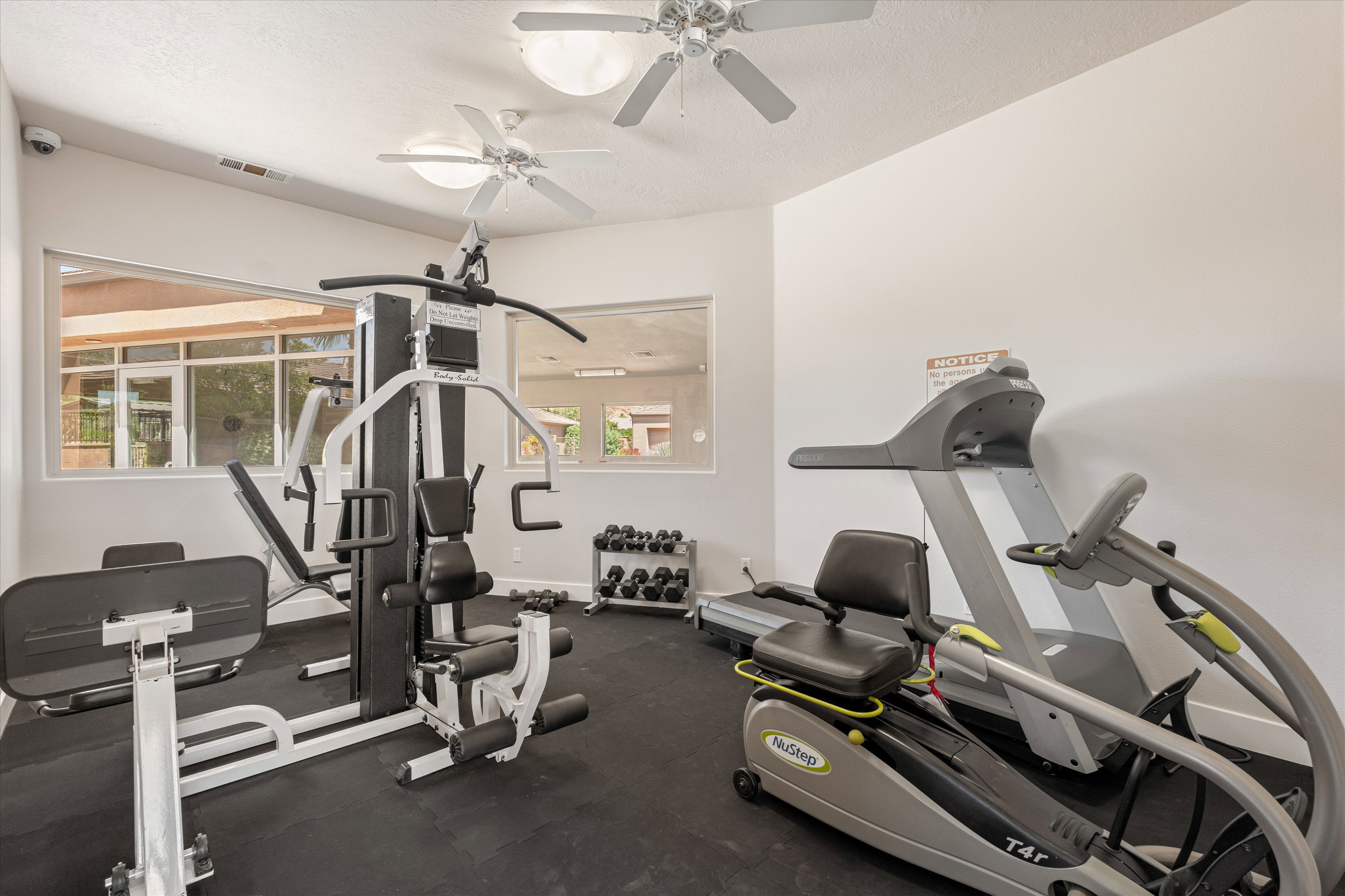 Dedicated fitness space featuring rubber flooring, two ceiling fans, and multiple windows