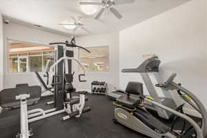 Dedicated fitness space featuring rubber flooring, two ceiling fans, and multiple windows