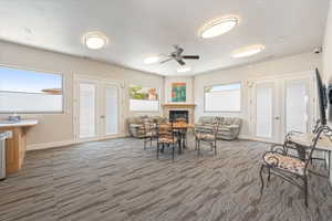 Spacious common area featuring patterned carpeting, multiple windows with blinds, and white double French doors