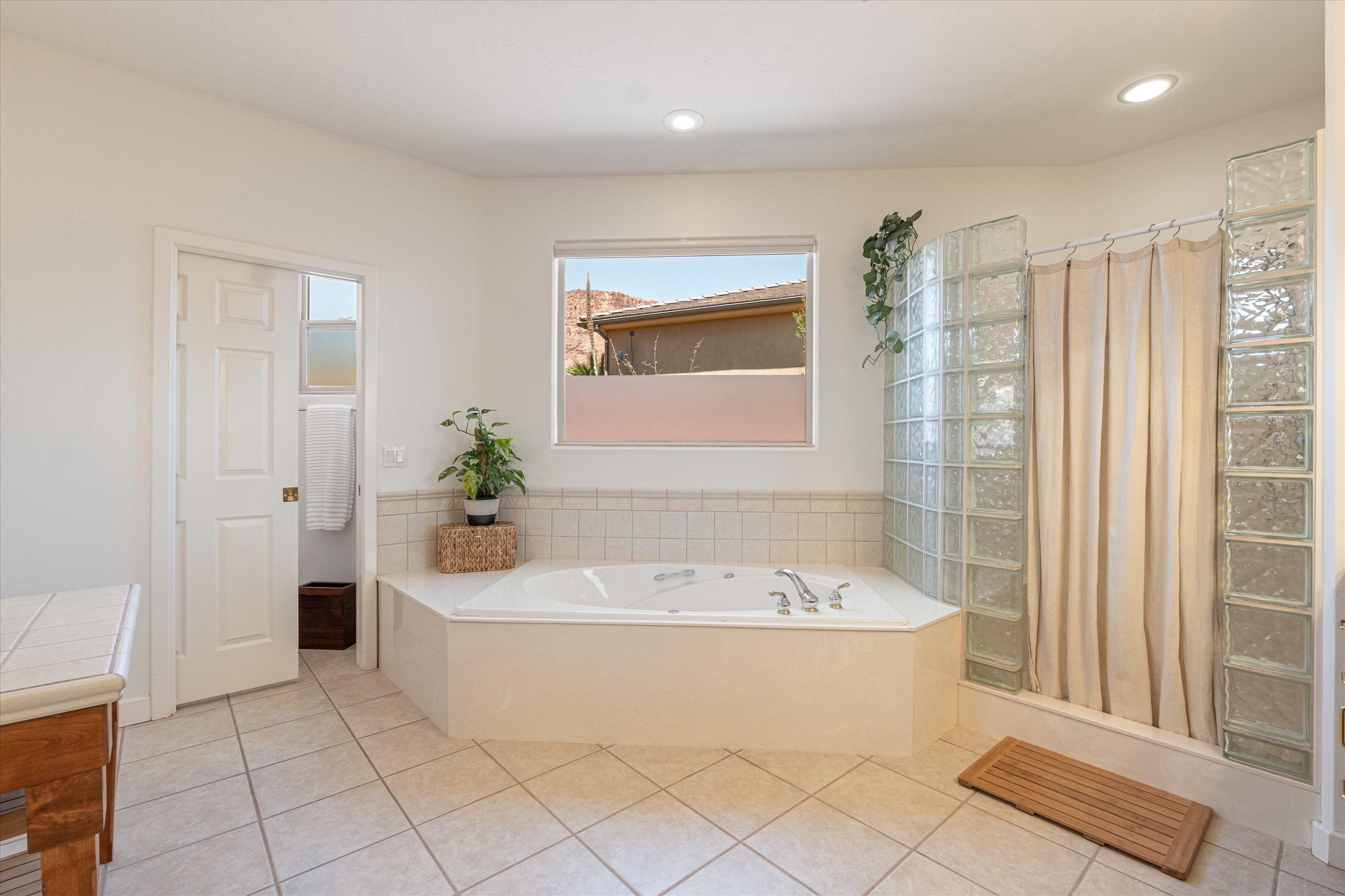 Soaking tub with tile surround, glass block shower enclosure, tile flooring, and recessed lighting