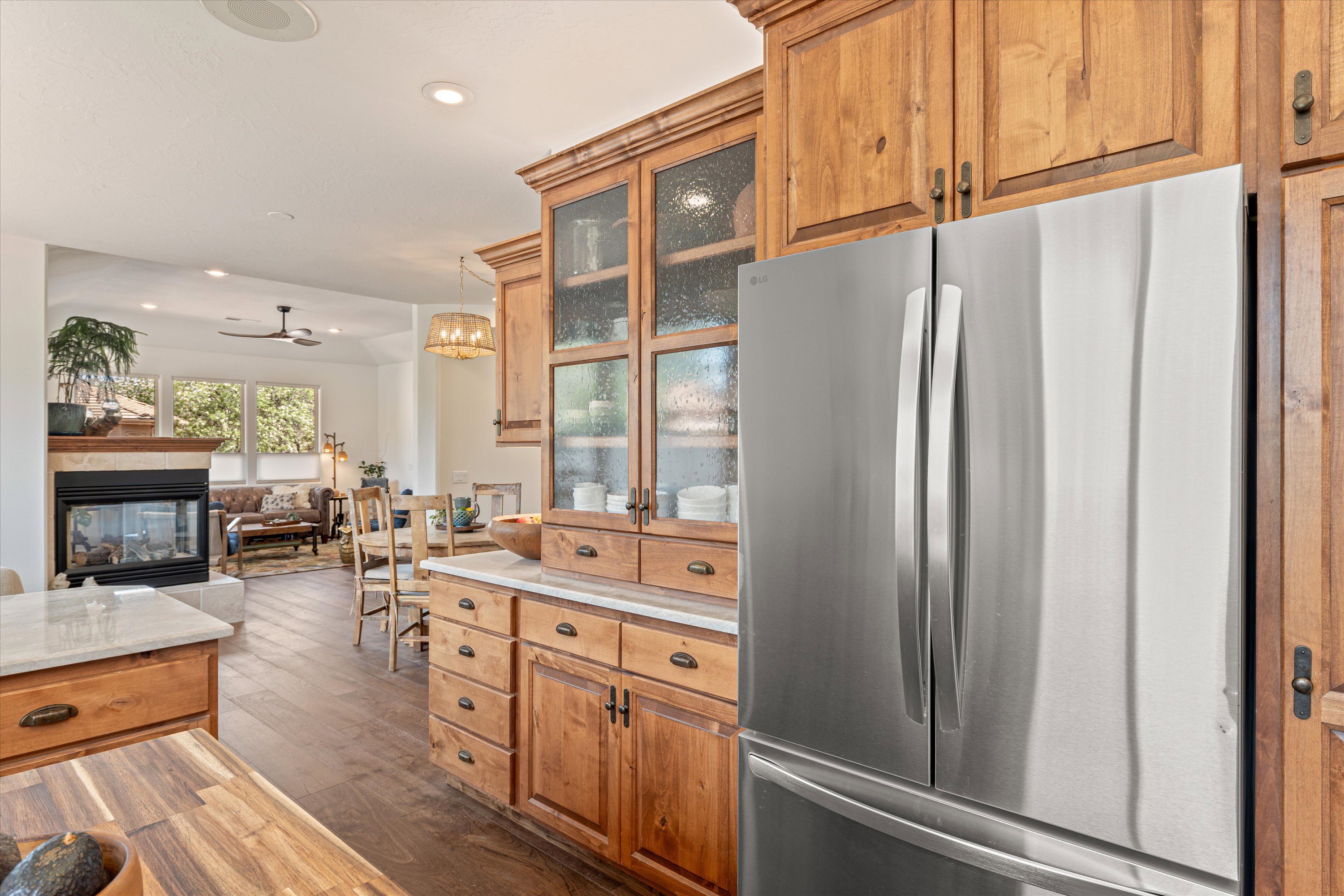 Kitchen featuring freestanding refrigerator, dark wood-type flooring, glass fronted cabinets, wood finish cabinets, and open floor plan