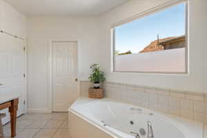 Corner soaking tub with deck-mounted fixtures, set against a tiled surround and a large horizontal window