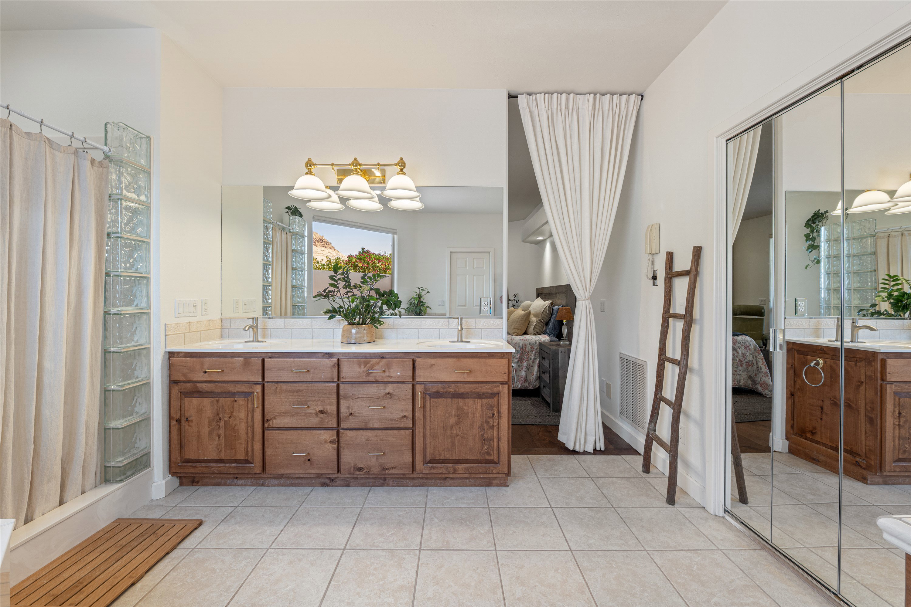 Bathroom featuring a dual vanity with wood cabinetry, a large mirror, and a wall-mounted light fixture