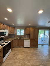 Kitchen featuring light wood cabinetry, stone-finish countertops, and a full tile backsplash