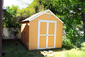 View of shed on the side of the house with a fenced backyard