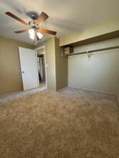 Plush brown carpeting throughout, complemented by a ceiling fan with wood-finish blades and integrated lighting