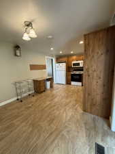 Kitchen area featuring wood-finish cabinetry, white appliances, and recessed lighting