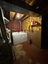 Dedicated laundry area featuring a washer and dryer set, exposed ceiling joists, and a utility sink