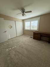 Carpeted room featuring a ceiling fan with integrated lighting, two sliding closet doors, and window with white plantation shutters