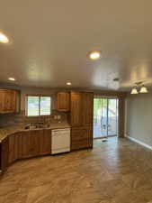 Kitchen and dining area featuring wood cabinetry with granite-style countertops, mosaic tile backsplash, and a double-basin sink
