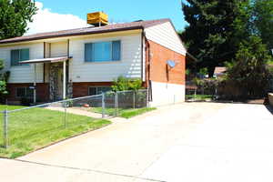 Bi-level home featuring a fenced front yard, a gate, driveway, and brick siding