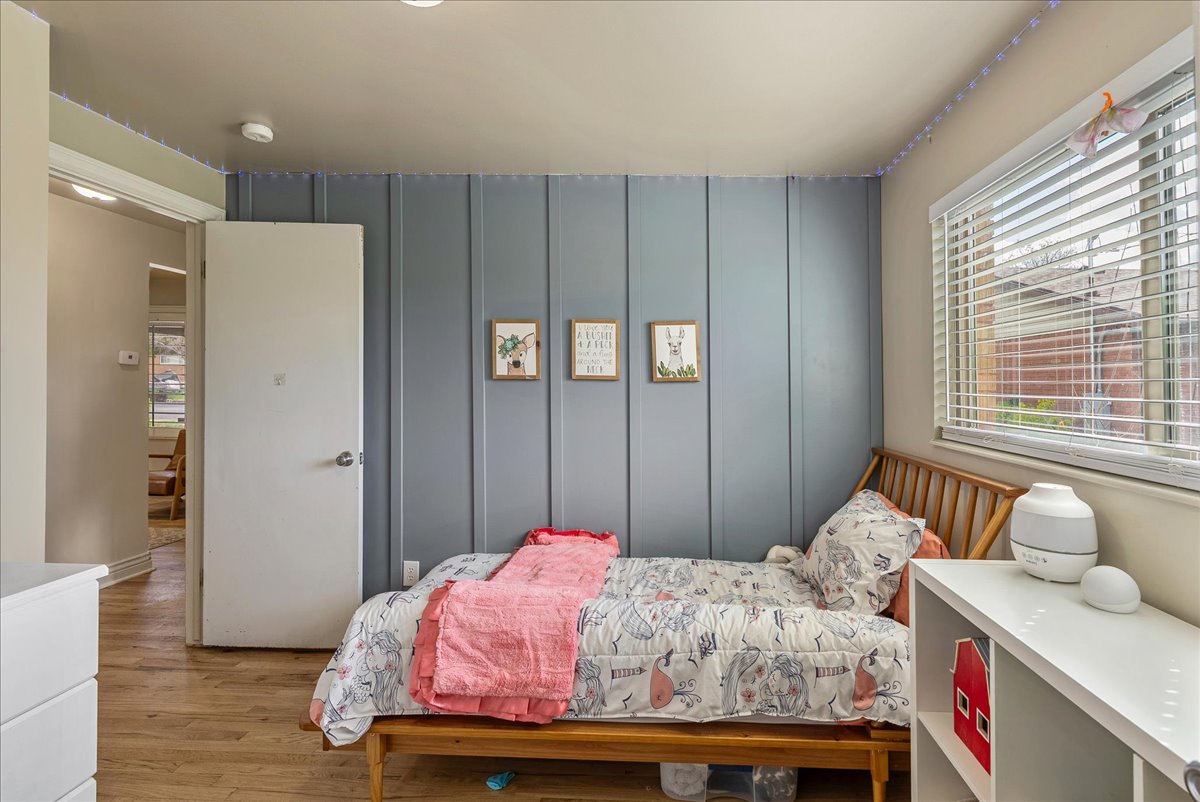 Bedroom featuring a decorative wall and light wood-style flooring