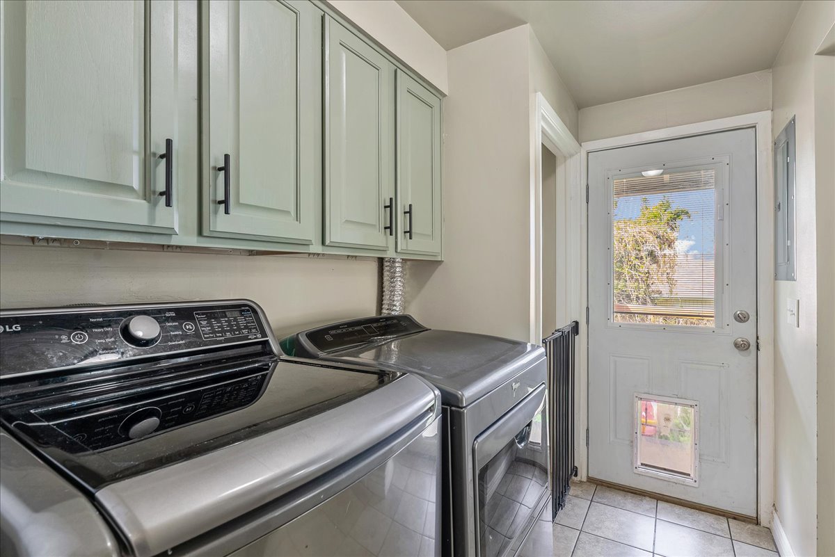 Laundry room featuring separate washer and dryer, cabinet space, and light tile patterned floors