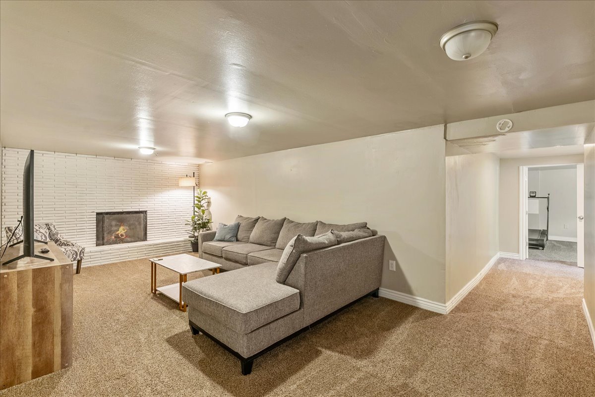 Carpeted living room with a brick fireplace and baseboards