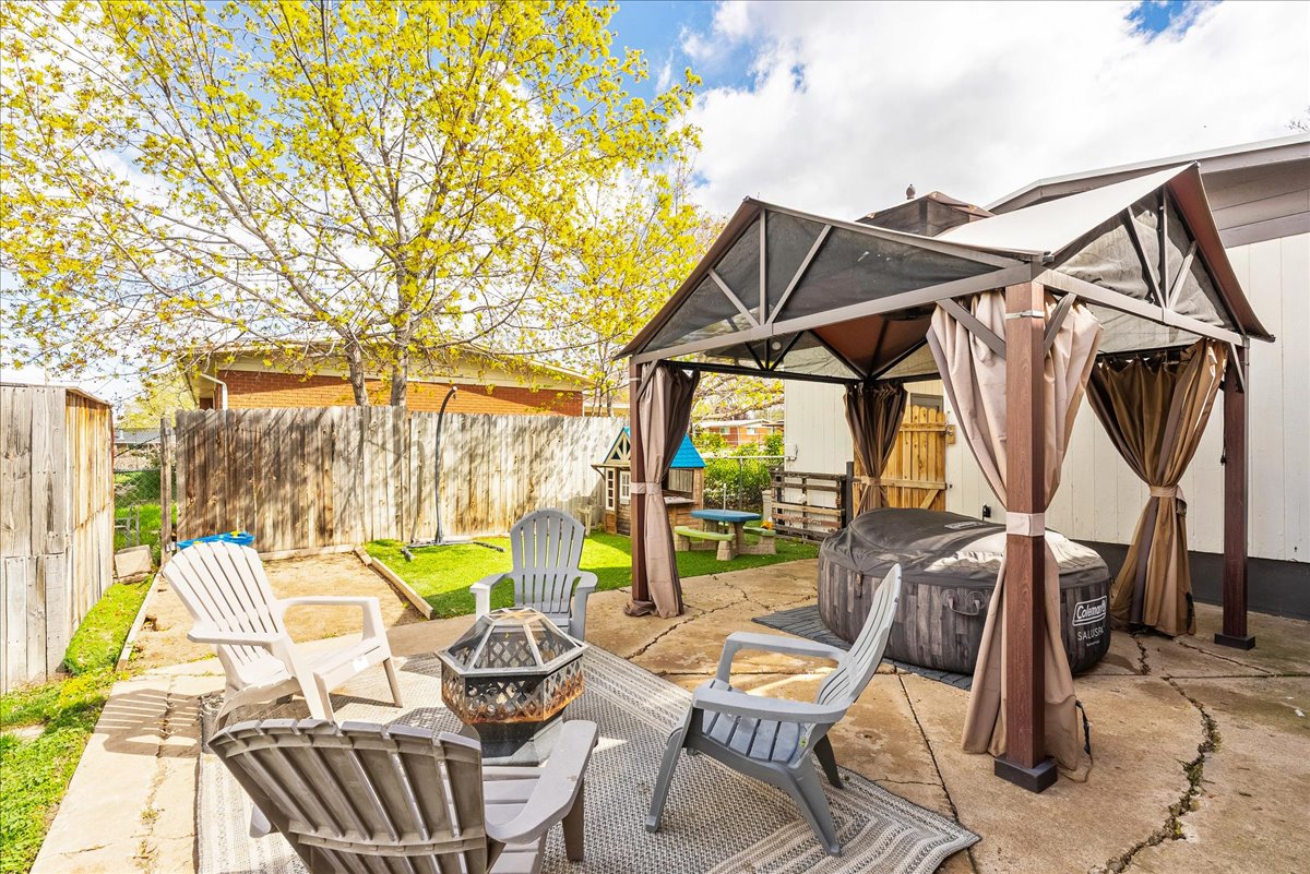 Fenced backyard with a patio area, a gazebo, an outdoor fire pit, and a hot tub