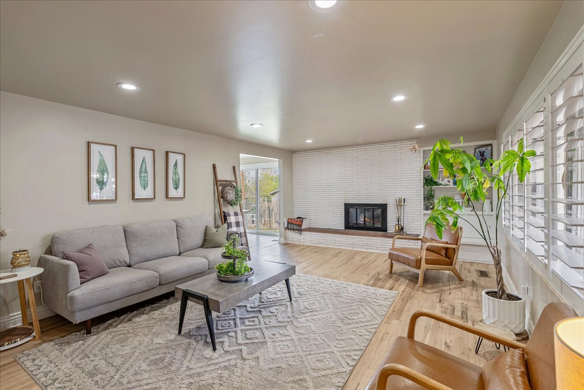 Living area with light wood-type flooring, recessed lighting, and a brick fireplace