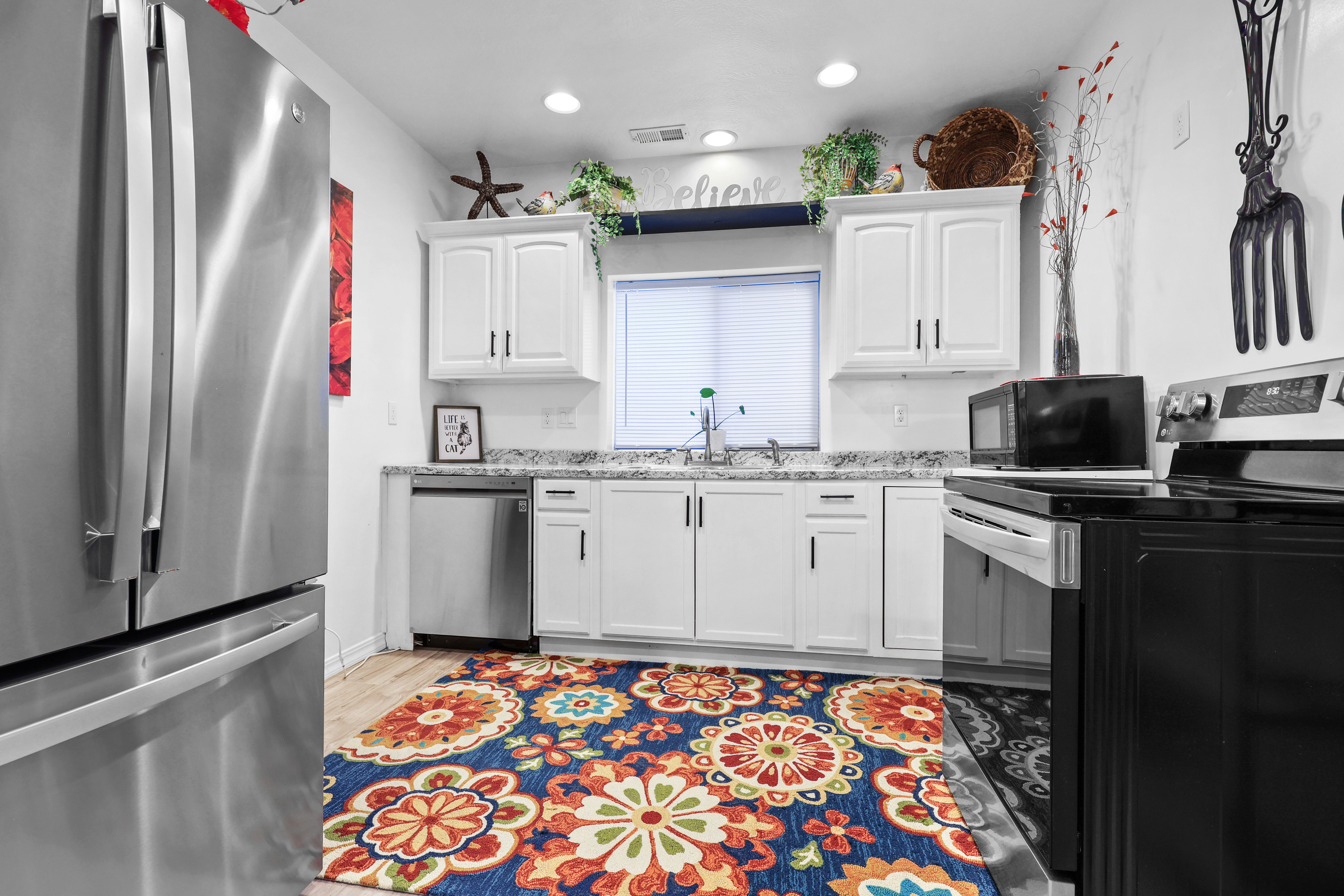 Kitchen with stainless steel appliances, white cabinets, light wood finished floors, light stone countertops, and recessed lighting