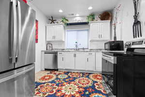 Kitchen with stainless steel appliances, white cabinets, light wood finished floors, light stone countertops, and recessed lighting