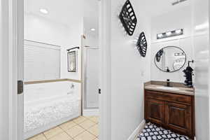 Bathroom featuring vanity, a shower stall, light tile patterned floors, and a bath