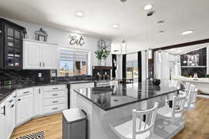 Kitchen with a breakfast bar, light wood-type flooring, a kitchen island, and dark stone countertops