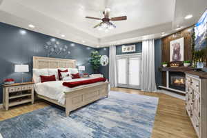 Bedroom featuring access to outside, recessed lighting, ceiling fan, light wood-style floors, and a glass covered fireplace