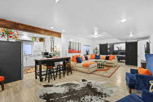 Living room featuring a barn door, light wood-style floors, and recessed lighting