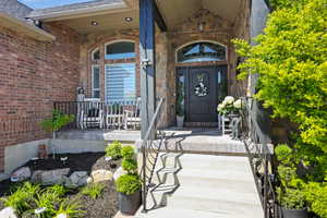 Entrance to property featuring covered porch and brick siding