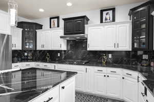 Kitchen with glass fronted cabinets, dark stone counters, white cabinets, stainless steel appliances, and recessed lighting