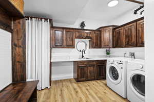 Laundry room featuring independent washer and dryer, light wood-style flooring, and cabinet space