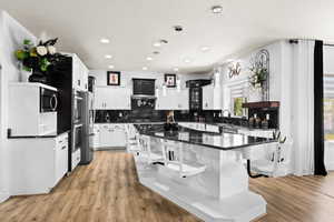 Kitchen with a kitchen island, pendant lighting, white cabinets, dark stone counters, and stainless steel appliances