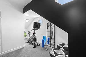Workout area with light colored carpet and lofted ceiling