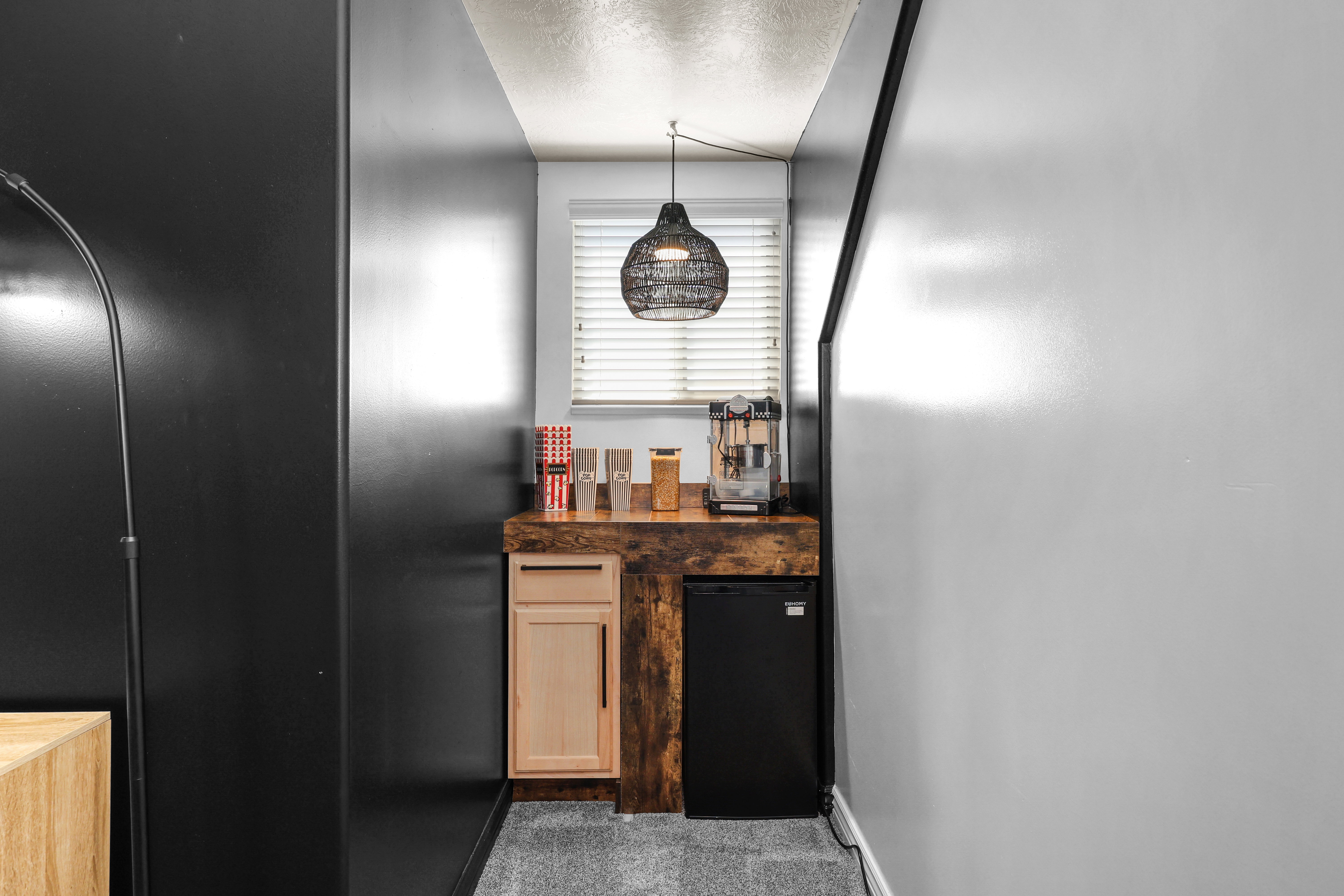 Kitchen featuring refrigerator, black fridge, a textured ceiling, pendant lighting, and light wood finish cabinetry