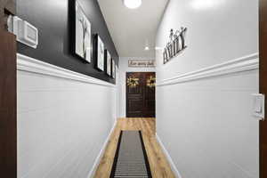 Doorway to outside featuring wood finished floors, a wainscoted wall, and recessed lighting