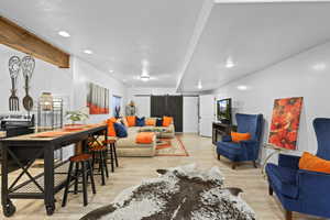 Living area featuring a barn door, light wood-style flooring, and recessed lighting