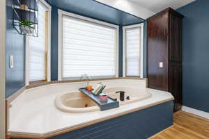 Full bath with a garden tub and light wood-style flooring